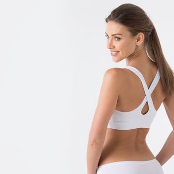 Young woman in white sport lingerie looking in profile . rear view , copy space for text
