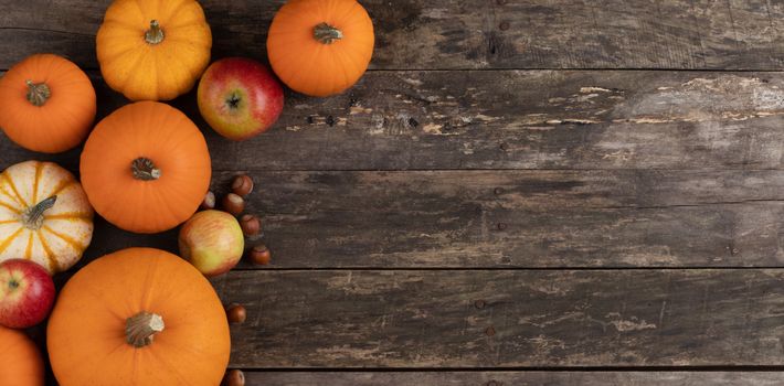Autumn harvest still life with pumpkins , apples , hazelnuts on wooden background , top view