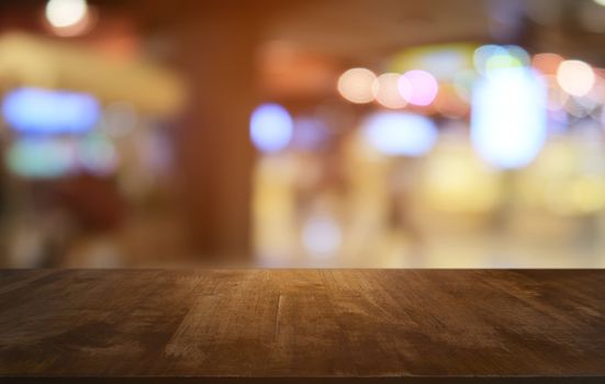 Empty dark wooden table in front of abstract blurred bokeh background of restaurant . can be used for display or montage your products.Mock up for space