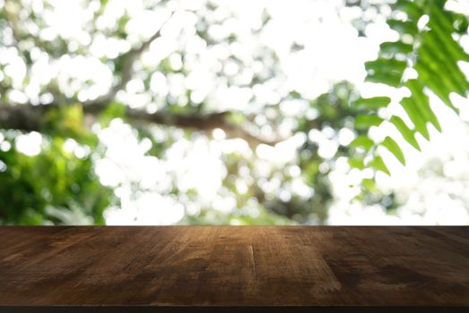 Image of dark wooden table in front of abstract blurred background of outdoor garden lights. can be used for display or montage your products.Mock up for display of product.