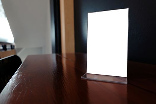 Mock up Menu frame standing on wood table in Bar restaurant cafe. space for text