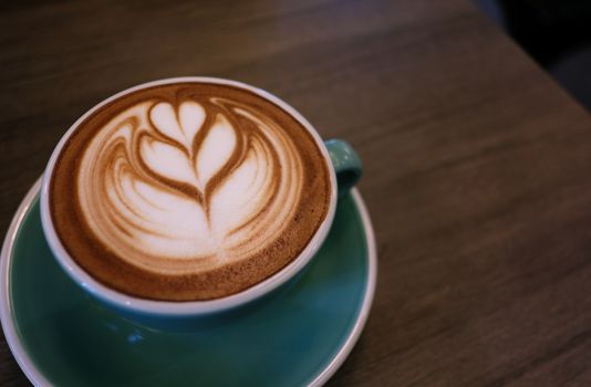 Cup of hot latte art coffee on wooden table