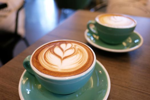 Cup of hot latte art coffee on wooden table