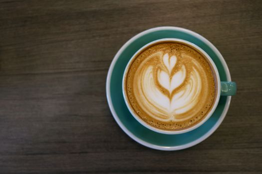 Cup of hot latte art coffee on wooden table