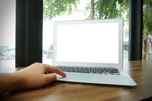 Laptop with blank screen on wooden table in front of coffeeshop cafe - technology concept.