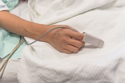Close-up pulse oximeter in a lady patient fingertip for heart rate and blood oxygen level monitoring at labor and delivery room