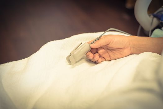 Close-up pulse oximeter in a lady patient fingertip for heart rate and blood oxygen level monitoring at labor and delivery room