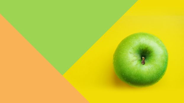 Green apple in water drops on yellow color background isolated close up macro top view