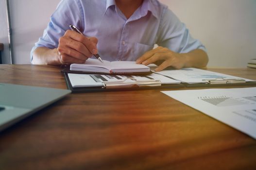 Businessman analyzing investment charts and pressing calculator buttons over documents. Accounting Concept.