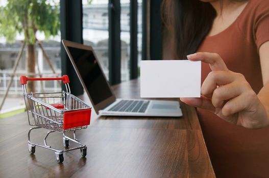 Small shopping cart with Laptop and business card copy space screen for shopping online concept