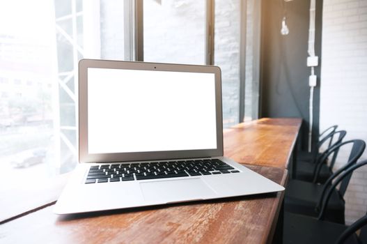 Laptop with blank screen on wooden table in front of office window