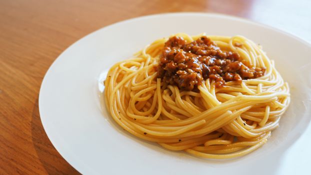 Plate of delicious spaghetti Bolognaise or Bolognese with savory minced beef and tomato sauce garnished, overhead view