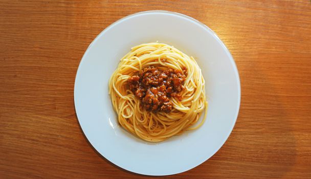 Plate of delicious spaghetti Bolognaise or Bolognese with savory minced beef and tomato sauce garnished, overhead view