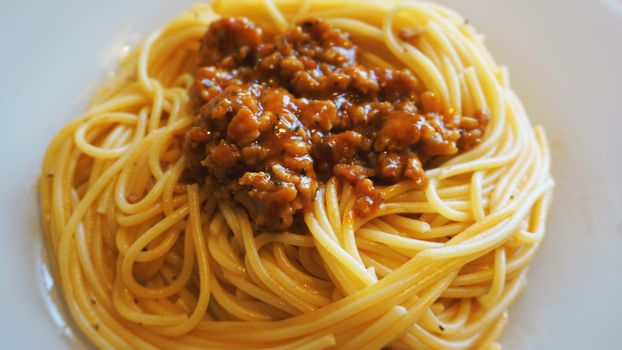 Plate of delicious spaghetti Bolognaise or Bolognese with savory minced beef and tomato sauce garnished, overhead view