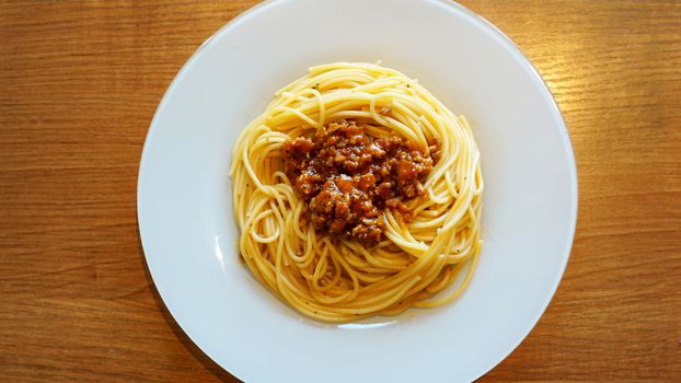 Plate of delicious spaghetti Bolognaise or Bolognese with savory minced beef and tomato sauce garnished, overhead view