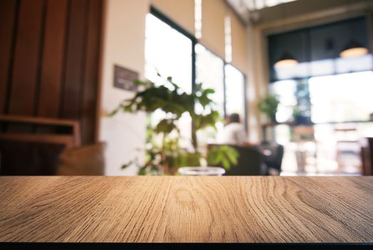 Empty wooden table in front of abstract blurred background of coffee shop . can be used for display or montage your products.Mock up for display of product.