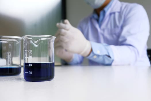 Male medical or scientific laboratory researcher performs tests with blue liquid in laboratory. equipment science experiments concept