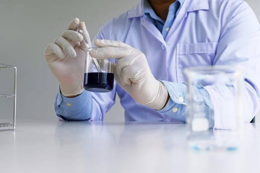 Male medical or scientific laboratory researcher performs tests with blue liquid in laboratory. equipment science experiments concept