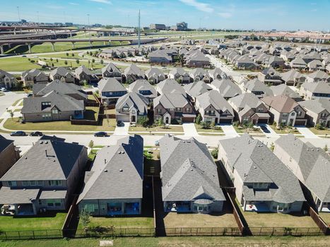 Top view new established neighborhood suburban Dallas, Texas, USA. Row of single-family houses with gardens near elevated highway viaduct