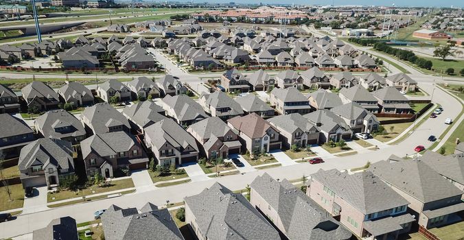 Top view new established neighborhood suburban Dallas, Texas, USA. Row of single-family houses with gardens near elevated highway viaduct