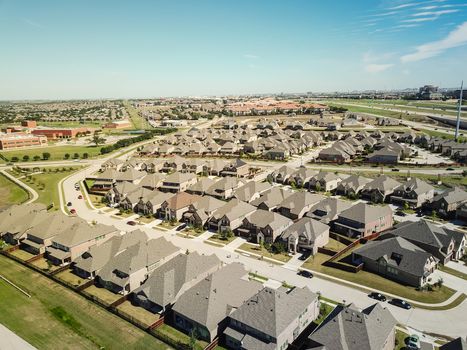 Aerial view new residential neighborhood situated between highway and school district near Dallas, Texas, USA. Row of single-family houses with gardens