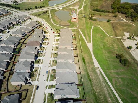 Top view new established neighborhood with brand new houses near park and pathway trail. Flyover residential area in suburban Dallas, Texas, USA