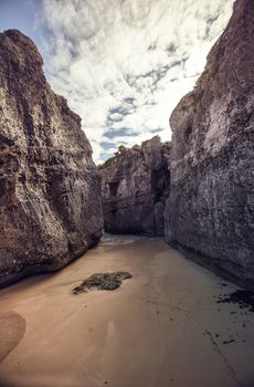 Rocky walls create a natural insenatira in the beach of the Tulum ruins in Mexico. Ertical shot. 