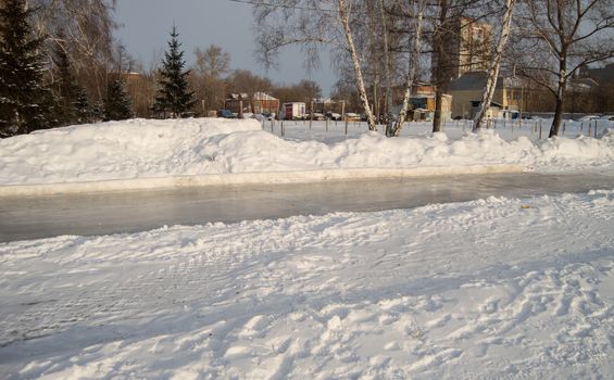 Winter landscape of the open city Park with ice skating track.