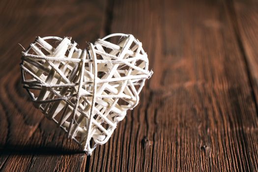 White wicker heart on old wooden background Valentine day