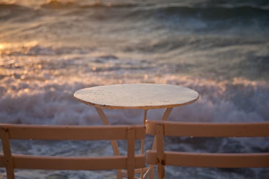 table and chairs near the waves at sunset - beach holiday