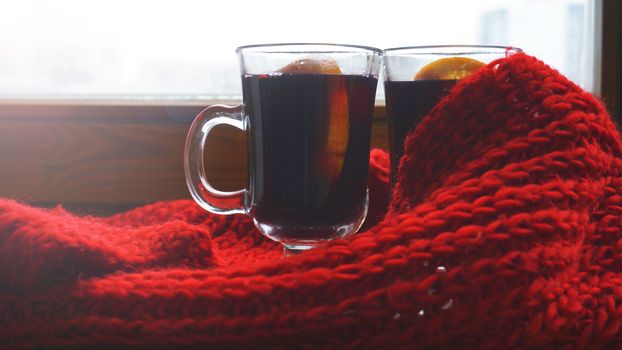 Hot Mulled Wine for winter and Christmas on wooden table with copy space. Red Hot wine with orange and red scarf