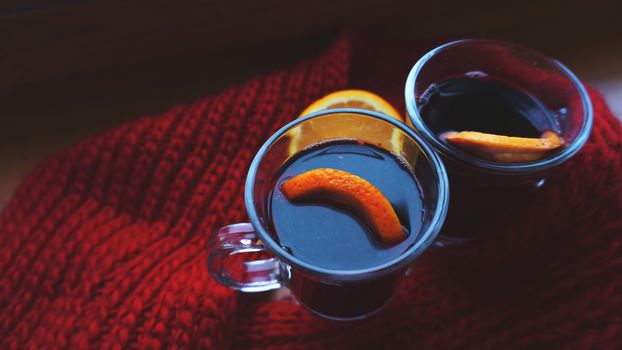 Hot Mulled Wine for winter and Christmas on wooden table with copy space. Red Hot wine with orange and red scarf