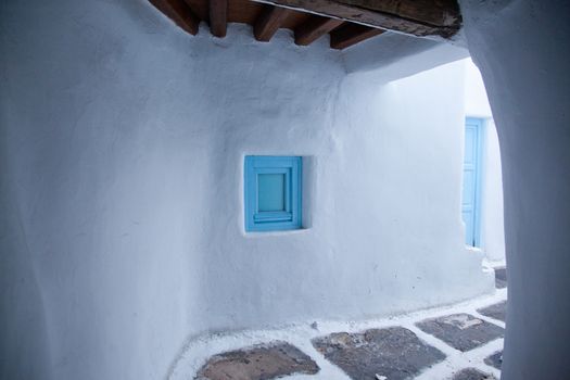 traditional narrow street in Mykonos with blue doors and white walls