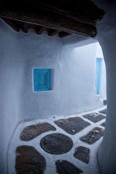 traditional narrow street in Mykonos with blue doors and white walls