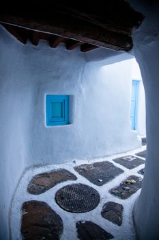 traditional narrow street in Mykonos with blue doors and white walls