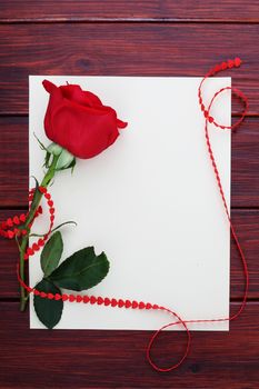 Red rose, paper and hearts ribbon on dark wooden background, Valentines day concept