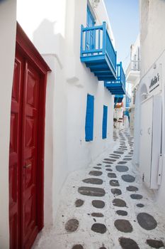 traditional narrow street in Mykonos with blue doors and white walls