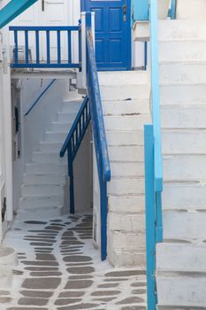 traditional narrow street in Mykonos with blue doors and white walls