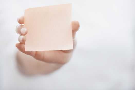 Human hand holding adhesive note