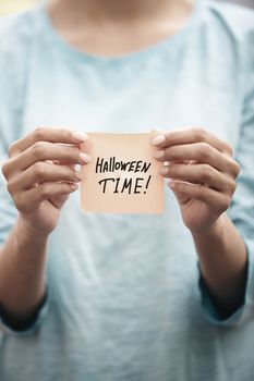 Woman holds adhesive note with Halloween time text