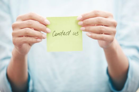 Yoga instructor holding sticky note with Contact us text