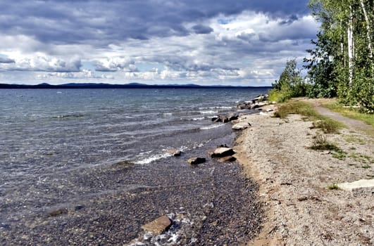 view of the lake with cumulonimbus clouds above it in windy weather