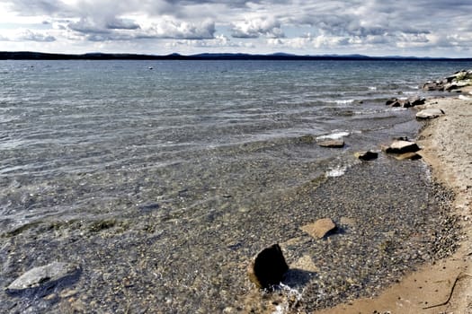 view of the lake with cumulonimbus clouds above it in windy weather