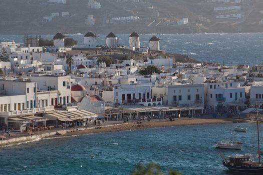 panoramic view of the Mykonos town harbor with famous windmills from the above hills on a sunny summer day, Mykonos, Cyclades, Greece 