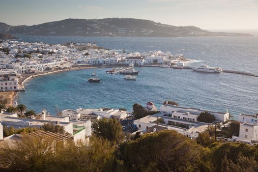 panoramic view of the Mykonos town harbor with famous windmills from the above hills on a sunny summer day, Mykonos, Cyclades, Greece 