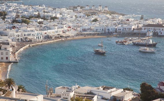 panoramic view of the Mykonos town harbor with famous windmills from the above hills on a sunny summer day, Mykonos, Cyclades, Greece 