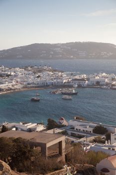 panoramic view of the Mykonos town harbor with famous windmills from the above hills on a sunny summer day, Mykonos, Cyclades, Greece 