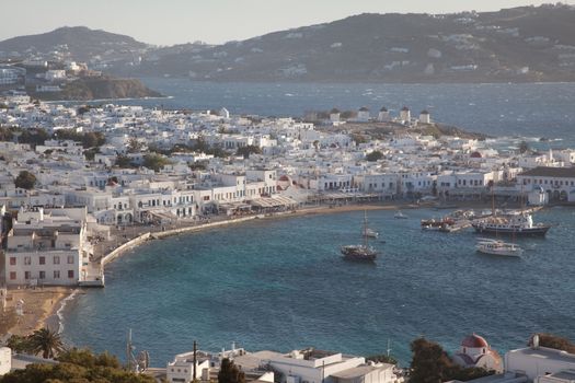 panoramic view of the Mykonos town harbor with famous windmills from the above hills on a sunny summer day, Mykonos, Cyclades, Greece 