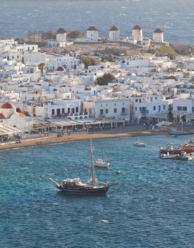 panoramic view of the Mykonos town harbor with famous windmills from the above hills on a sunny summer day, Mykonos, Cyclades, Greece 