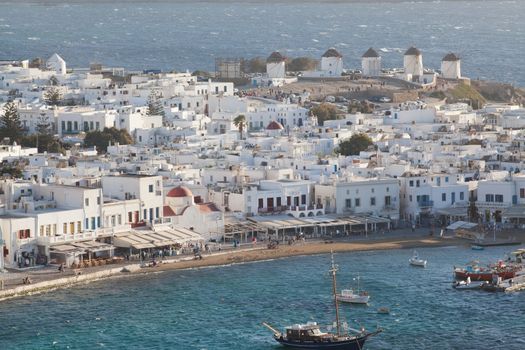 panoramic view of the Mykonos town harbor with famous windmills from the above hills on a sunny summer day, Mykonos, Cyclades, Greece 